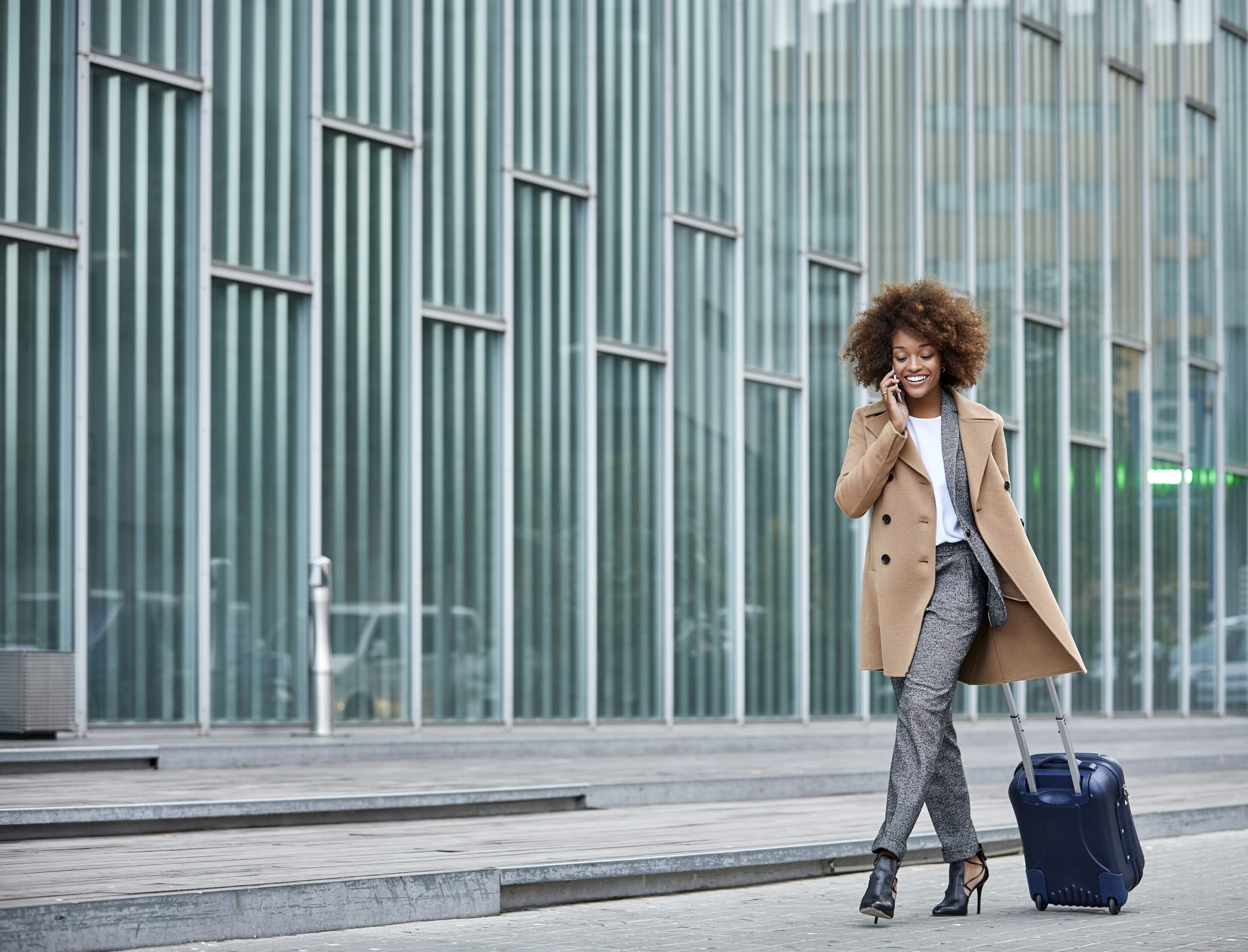 Businesswoman with luggage talking on smart phone